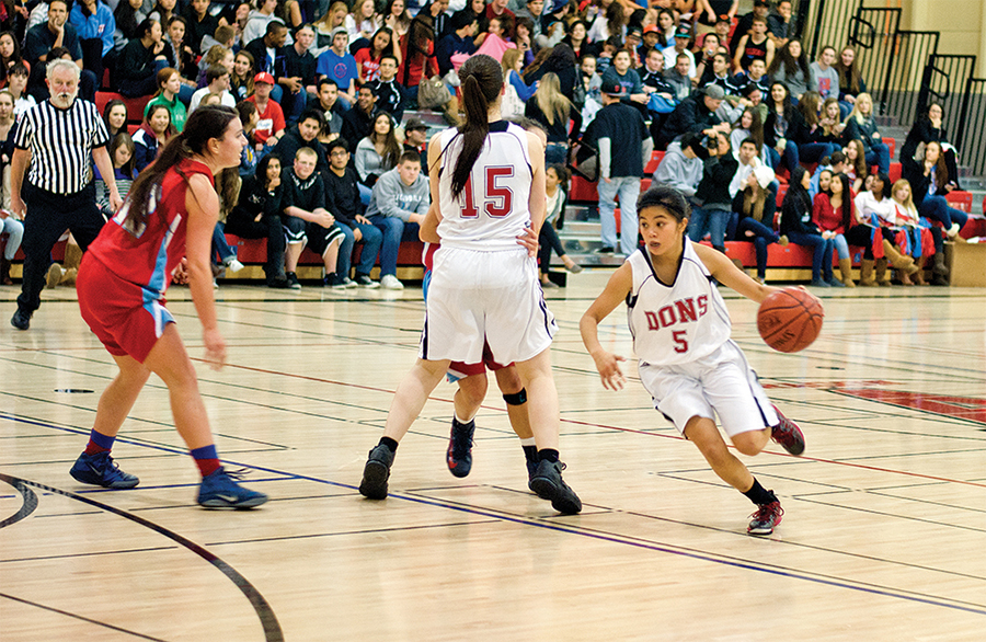 Aragon High School Junior Alyssa Mangaoang dribbles past a Hillsdale High School defender as senior Corie Stocker watches after setting a pick, in their basketball game.