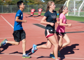 Cross country team members condition on the track during an afternoon practice.