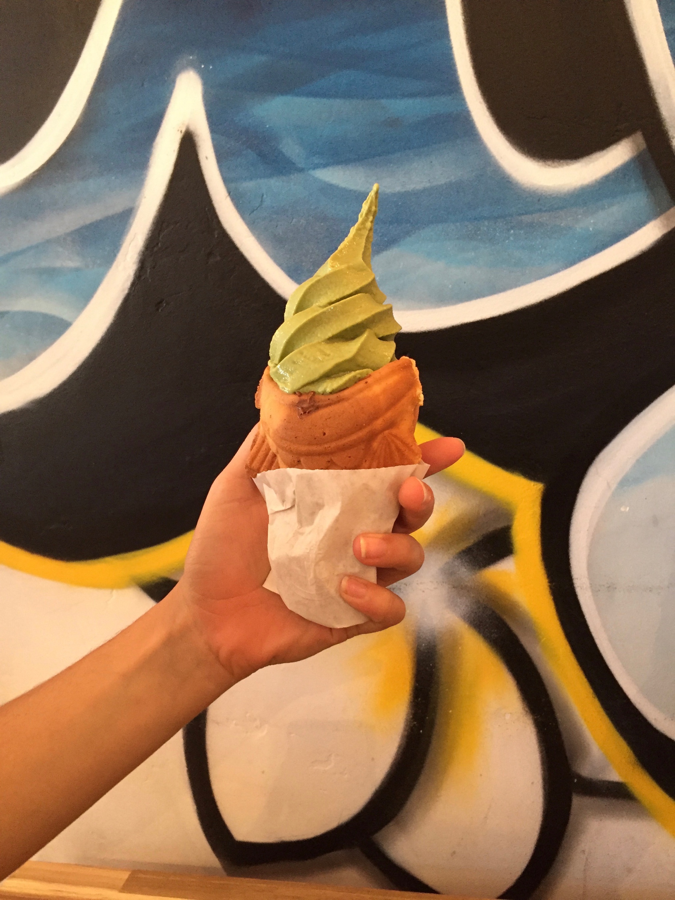 Uji Time matcha ice cream against colorful wall.